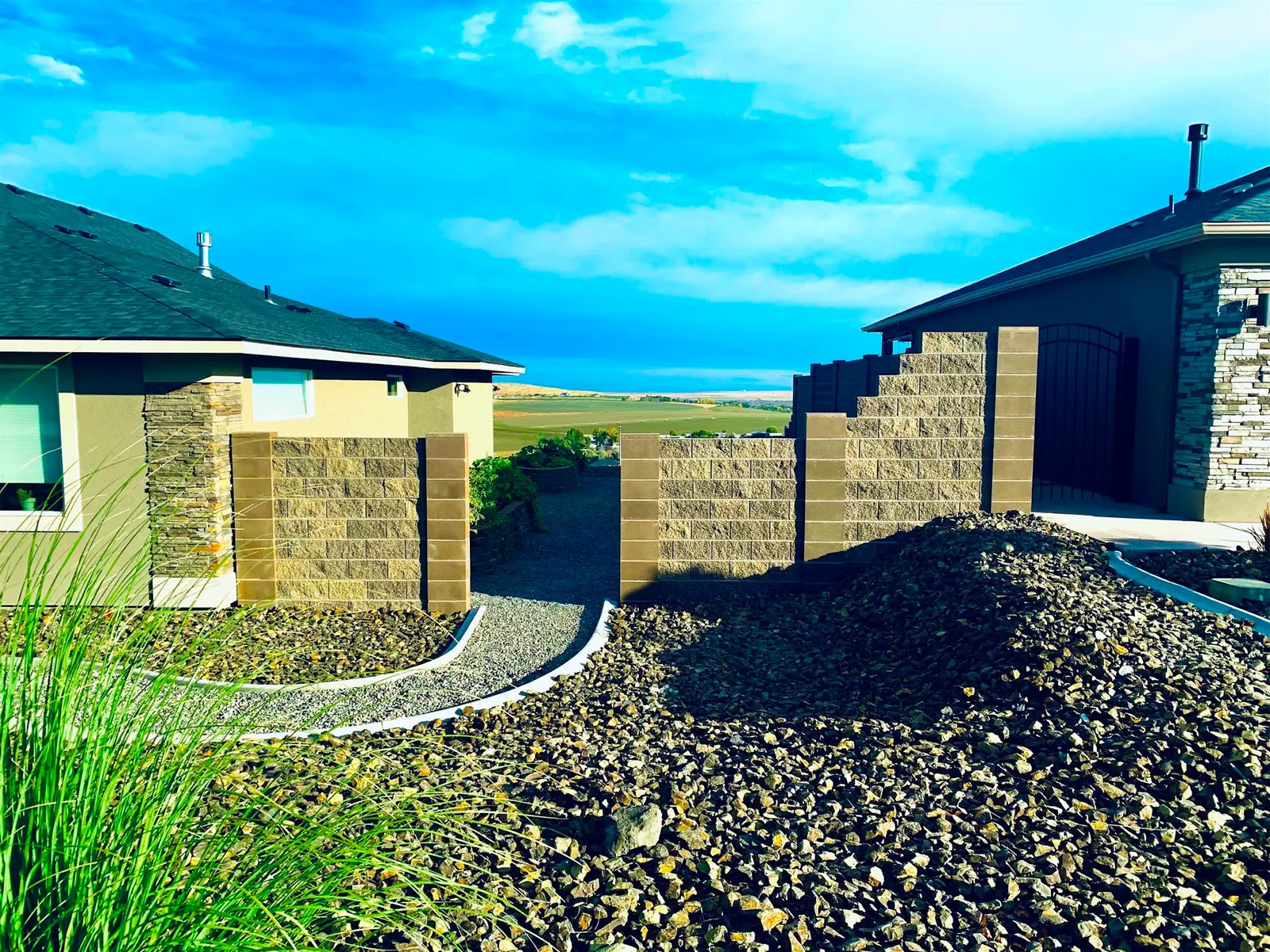 Gravel bed and stone block walls beside a lawn under a blue sky
