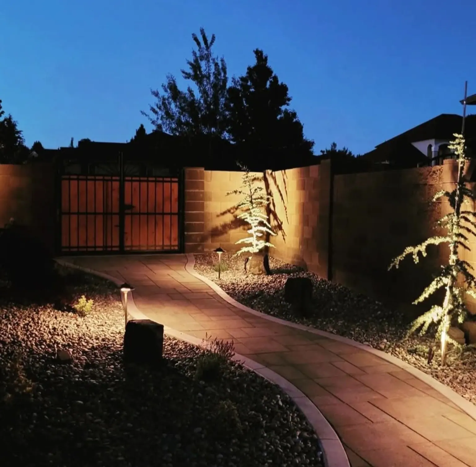 Lit paver path and gate at night