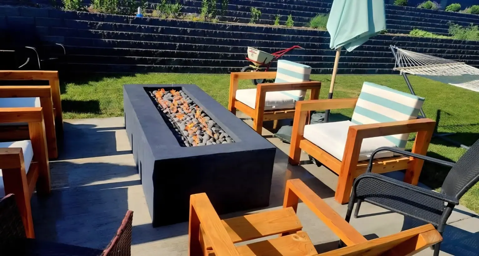 Fire table with wood patio chairs on a lawn